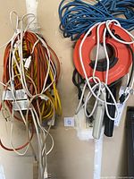 Wall view of multiple coiled extension cords and red cord reel with blue cable