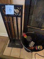 fireplace tool stand with tools and ash bucket beside hearth