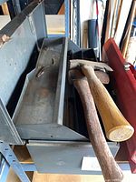 Grey metal toolbox open with trays visible and two hatchets resting on top