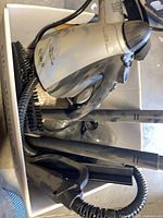 Box containing Shark handheld steam cleaner, hose, wands, brush, squeegee