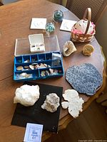 Overview of all items on table including minerals, fossils, paperweight, tiles and basket