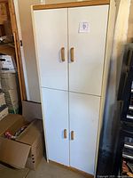 Full view of tall white cabinet with four doors and wood trim