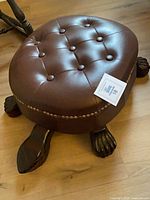 Full view of turtle foot stool showing leather top and carved wooden limbs
