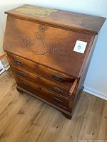 Closed secretary cabinet showing carved shell motif and three drawers