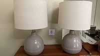 Two matching ceramic lamps with shades on tabletop