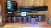 Stacked bowls and plates with mugs on cabinet shelf