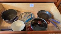 Drawer view of entire cookware set showing two frying pans, saucepan, square pot and two lids