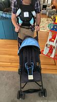 Stroller front view alongside person demonstrating baby carrier