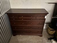 Front view of dark brown nine-drawer wood dresser