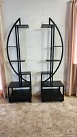 Two identical black half-moon plant stands side by side showing all shelves and base units