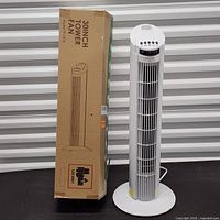 Tower fan standing beside its original box