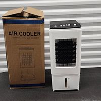 Air cooler standing next to original box showing product and packaging