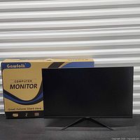Monitor on stand in front of branded box, screen powered off