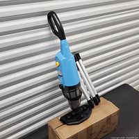 Handheld pool vacuum cleaner with pole sections standing on box