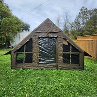 Front view of brown inflatable tent with clear PVC door and mesh windows set up on grass
