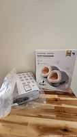 Foot massager unit in plastic next to retail box