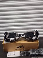 Hoverboard resting on original box with charger and manual visible