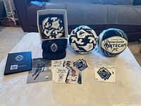 full lot on table showing three signed balls, hat, book, cards, decals