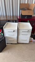 Two white 3-drawer mobile filing cabinets on casters side by side