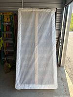 Front view of one box spring half, white fabric border, vertical support strip visible through dust cover