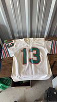 Front view of white Miami Dolphins #13 jersey laid flat