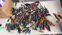 Pile of assorted screwdrivers spread on table