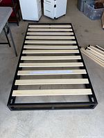 Top view of assembled twin bed frame showing metal perimeter and wooden slats