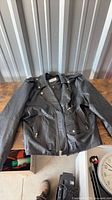 Full view of black leather motorcycle jacket on table