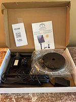 Open box showing kit contents: solar panel, pump with cord, foam float, tubing, fittings, manual