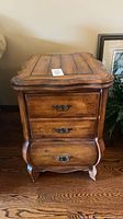 Three-quarter front view of the French Provincial end table showing drawers and brass-tone pulls