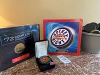 Group shot of all four items: sealed ’72 Complete box set, sealed HNIC game, signed puck in case, bucket of loose pucks