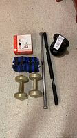 All items laid out: kettlebell, dumbbells, ankle weights, two bars, boxed Pilates kit