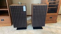 Front view of both JBL L100 speakers on stands with wire coils visible