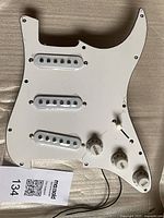 Front of white pickguard with pickups, knobs and wiring leads visible