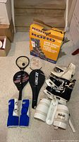 Group shot of all items including skates, racquets with covers, protective pads, and KOHO box