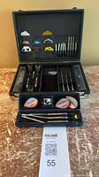 Large hard case open showing multiple sets of darts, spare parts, and slim case in front