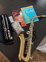 Overall lot showing saxophone, flute in case, books, reeds, accessories