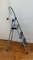 Full view of grey Cosco folding step ladder with two steps and handle