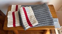 Folded grey, cream and red striped Roots throw blanket