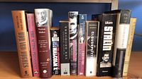 Full group shot of 11 hardcover books standing on shelf