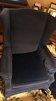 Front view of navy blue wingback armchair showing seat cushion and winged backrest