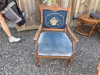 Front view of antique wooden armchair showing embroidered backrest and velvet seat