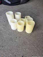 Eight ivory flameless pillar candles of various heights on concrete floor