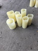 Seven ivory flameless LED pillar candles grouped on floor