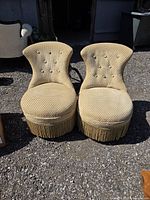 Front view of both gold slipper chairs showing upholstery, tufting and fringe
