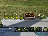 All items on railing: six green jar lanterns, one green votive, wooden crate with four gold cups, three succulent pots
