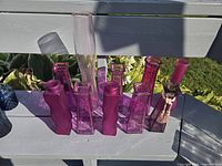 Group of 11 pink glass vases arranged on railing