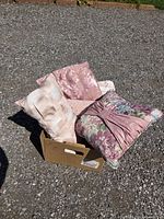 Group of five patterned pink throw pillows on gravel surface