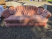 Front view of pink tufted velvet couch with two matching round pillows
