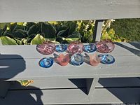 All twelve glass candle holders arranged on bench